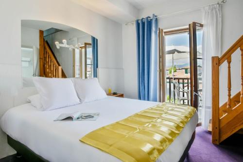 a bedroom with a large bed and a balcony at Logis Hotel & Restaurant Bergeret Sport in Hendaye