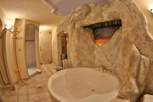 a bathroom with a large bath tub in a rock wall at Gästehaus - Apart Braito in Grän