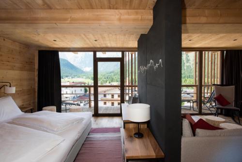 a bedroom with a bed and a large window at Berghotel - Sexten in Sesto