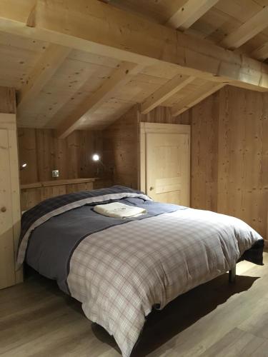 un grand lit dans une chambre aux murs en bois dans l'établissement Chalet La R'Batte, à Sixt-Fer-à-Cheval