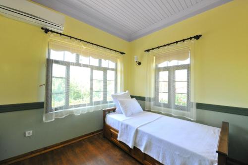 a bedroom with a bed and two windows at Petrino Gökçeada Hotel&Kitchen in Gokceada Town