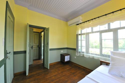 Schlafzimmer mit gelben Wänden, einem Bett und Fenstern in der Unterkunft Petrino Gökçeada Hotel&Kitchen in Gokceada Town