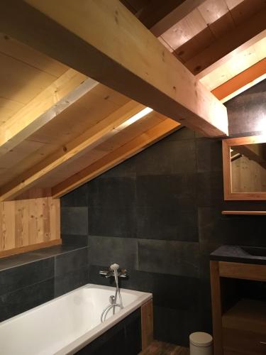 Cette chambre dispose d'une baignoire et d'un plafond en bois. dans l'établissement Chalet La R'Batte, à Sixt-Fer-à-Cheval