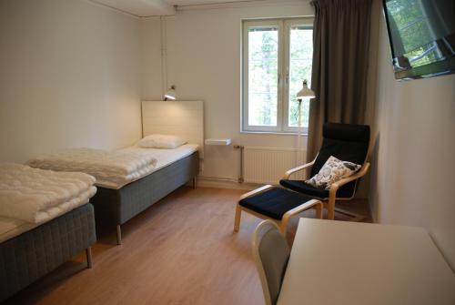 ein Hotelzimmer mit einem Bett, einem Stuhl und einem Fenster in der Unterkunft Strömbäcks Vandrarhem in Umeå