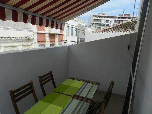 einen Tisch und Stühle auf einem Balkon mit einem grünen Tisch und Stühlen in der Unterkunft Casa Da Baixa in Faro