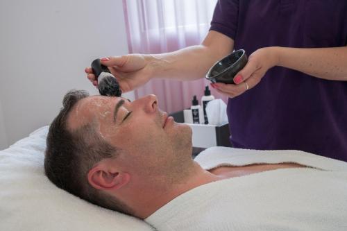 a man laying in a bed getting his hair cut at Best Western Plus Kurhotel an der Obermaintherme in Bad Staffelstein