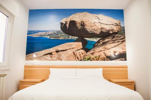 1 dormitorio con una gran pintura de roca en la pared en Hospedium Morada da Moa, en O Pindo