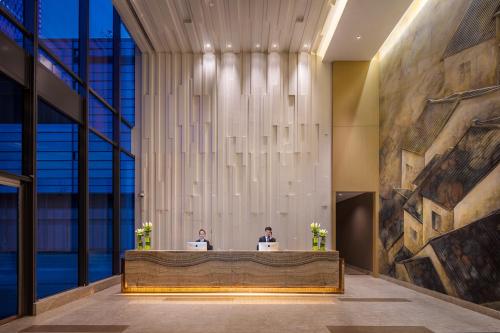 two people sitting at a reception desk in a lobby at Somerset Baitang Suzhou in Suzhou