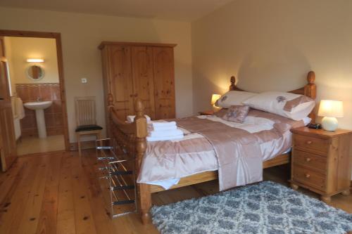 een slaapkamer met een groot bed en een houten dressoir bij THISTLEDOWN - Ballina - Crossmolina - County Mayo - Sleeps 8 - Sister property to Inglewood in Ballina