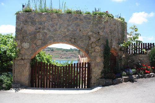 a stone gate with a fence and flowers at Zimer Al-Bayt in Mas'ade