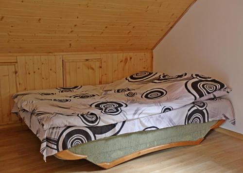 a bed in a room with a wooden ceiling at Domek nad Narwią in Długosiodło