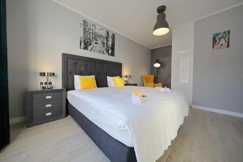 a bedroom with a large white bed with yellow pillows at City Marine Luxury Apartments in Zadar