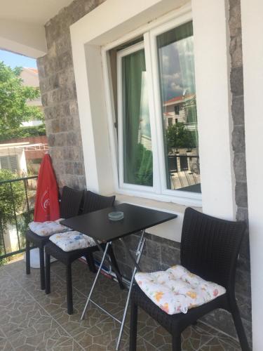 un patio con tavolo, sedie e finestra di Studio Apartments Krasici a Tivat