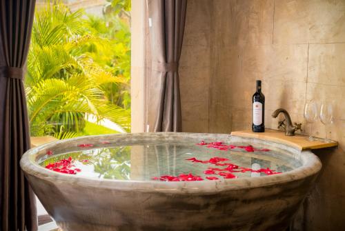a bath tub with a bottle of wine and red flowers at Model Temple Resort & Spa in Siem Reap