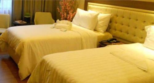 a hotel room with two beds with white sheets at ACE Hotel and Suites in Manila