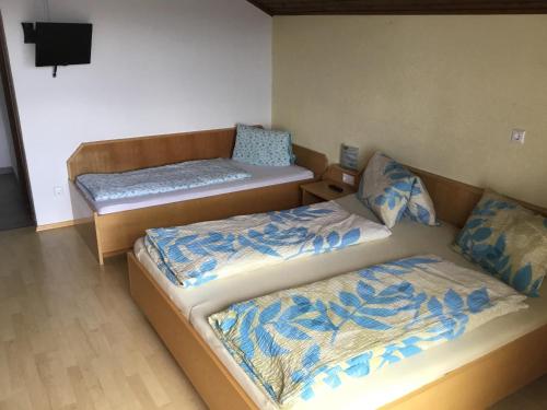 a room with two beds and a tv on the wall at Gasthof Wadl in Feldkirchen in Kärnten
