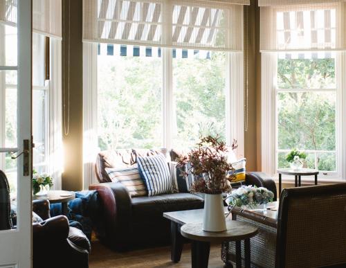 a living room with a couch and large windows at Bells at Killcare Boutique Hotel, Restaurant & Spa in Killcare
