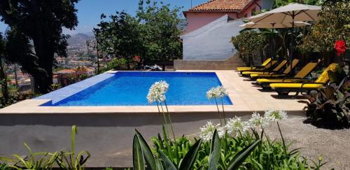 - une piscine avec des chaises jaunes et un parasol dans l'établissement Quinta do Bom Sucesso, à Funchal