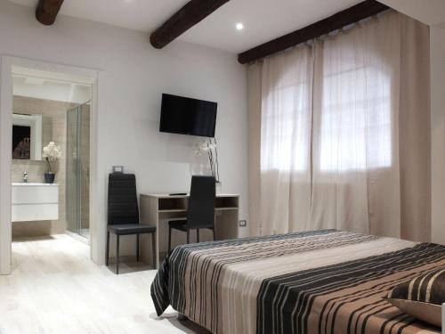 a bedroom with a bed and a desk and a television at Centro Storico Rooms in Ferrara
