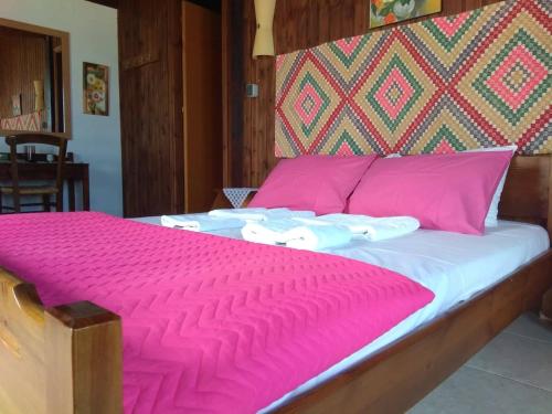 a bed with a pink comforter and pillows at Hotel Mochlos in Mochlos