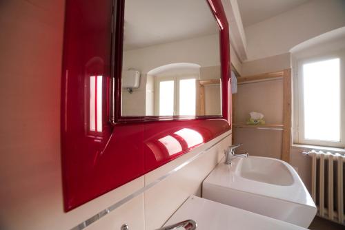 bagno con specchio rosso e lavandino di Almayer La Locanda a Gaeta