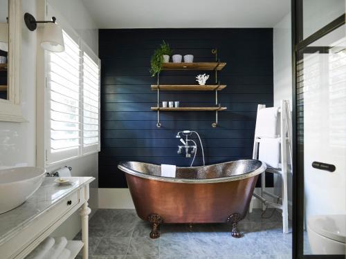 uma casa de banho com uma banheira de cobre e paredes pretas em Bells at Killcare Boutique Hotel, Restaurant & Spa em Killcare