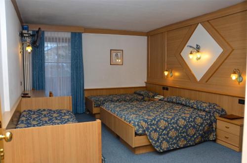 a hotel room with two beds and a window at Hotel Stella Alpina in Moena