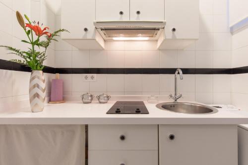 uma cozinha branca com um lavatório e um vaso de flores em Precioso Apartamento Sevilla Centro em Sevilha