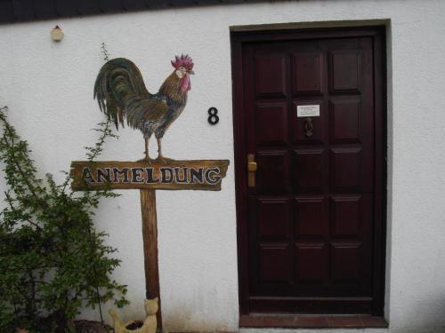 a sign with a rooster on it next to a door at Ferienhaus Uklei in Sielbeck
