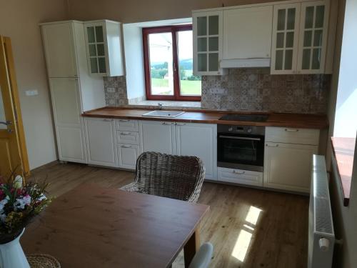 a kitchen with white cabinets and a table and a window at Chalupa u lesa - Nova Ves in Český Rudolec