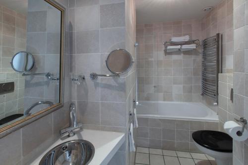 a bathroom with a tub and a toilet and a sink at Dutch Masters Short Stay Apartments in Amsterdam