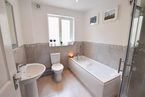 a bathroom with a tub and a toilet and a sink at Hillyard Mews in Newcastle