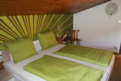 een wit bed met groene lakens en kussens in een kamer bij Watscherhof in Luson