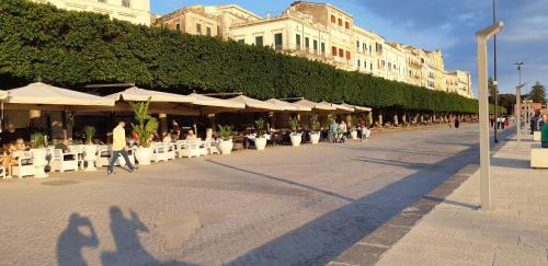 a group of people walking down a street with chairs and umbrellas at La Colombaia Di Ortigia in Siracusa