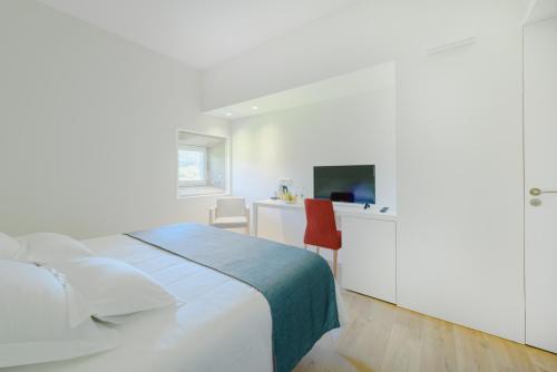 a white bedroom with a bed and a tv at Torre de Tebra in Tomiño