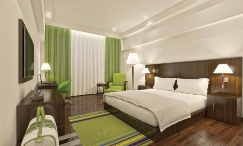 a bedroom with a large bed and a green chair at Regenta Central Hestia Dahej, Bhensali in Dahej