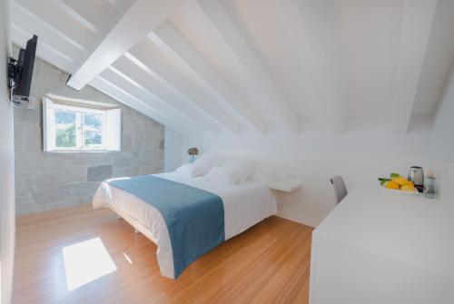 a white bedroom with a bed and a window at Torre de Tebra in Tomiño