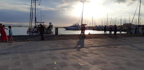 a group of people standing on a dock with boats at La Colombaia Di Ortigia in Siracusa