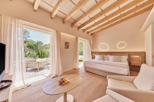 a bedroom with a bed and a couch and a tv at Pleta de Mar, Grand Luxury Hotel by Nature - Adults Only in Canyamel
