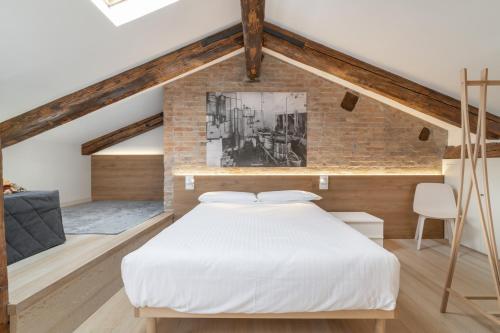 a bedroom with a white bed and a brick wall at Poli Grappa Suite in Venice