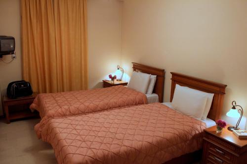 a hotel room with two beds with orange comforter at Famissi Hotel in Kalabaka