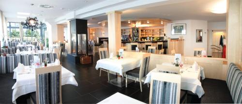 a restaurant with white tables and chairs in a room at Hotel Bergblick in Nauders