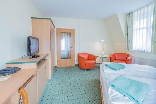 a hospital room with a bed and a tv and chairs at Am Weststrand Aparthotel Kühlungsborn in Kühlungsborn