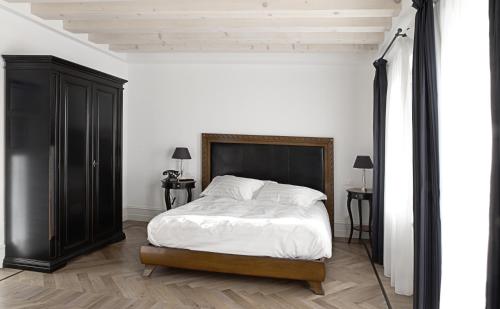 a bedroom with a large bed and a black cabinet at La Locanda alla Stazione in Ponte nellʼAlpi