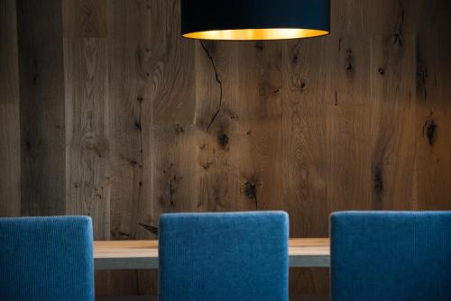 three blue chairs in front of a table with a light at Appartements Bergheim St Andrä bei Brixen in Bressanone