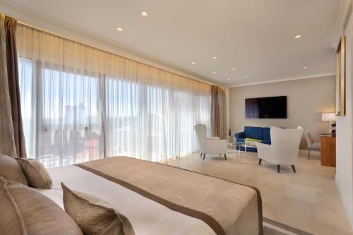 a bedroom with a large bed and a living room at Herbert Samuel Jerusalem in Jerusalem