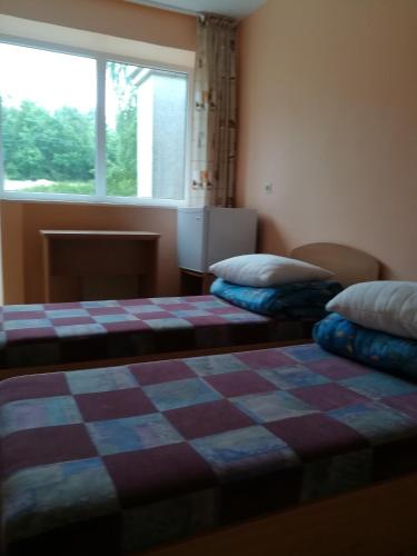 two beds in a room with a checkered blanket at Poilsio namai Šaltinelis in Plateliai