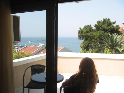 a girl sitting on a balcony looking out at the ocean at Kumsal Butik Otel in Istanbul