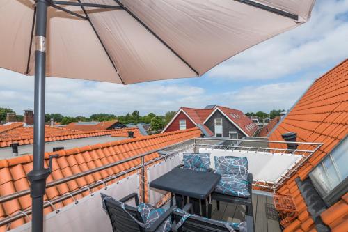 a patio with an umbrella and chairs on a balcony at Weststraat 22 - Ouddorp - Appartement Oost 3P in Ouddorp
