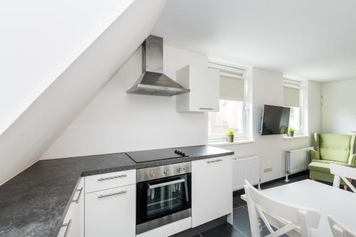 a kitchen with white cabinets and a dining room with a table at Weststraat 22 - Ouddorp - Appartement Oost 3P in Ouddorp